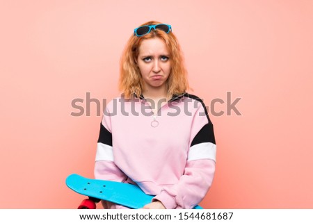 Young skater woman over isolated pink background sad