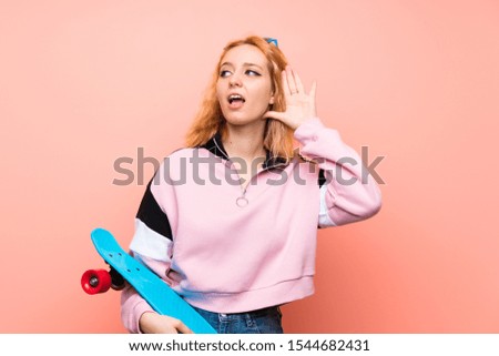 Young skater woman over isolated pink background listening something