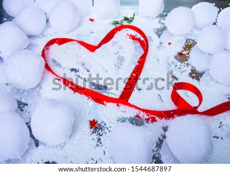 Heart-picture in the snow. A red heart love letter in ribbin on a bed of snow, ice and swowballs. 