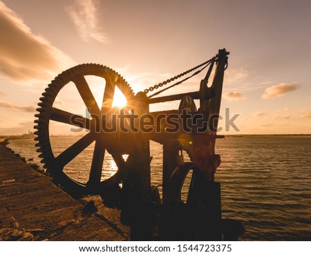 An old crane pictured next to Poolbeg lighthouse at sunset in Dublin, Ireland
