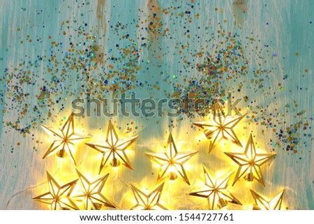 holidays concept of Christmas warm gold garland lights over wooden blue background
