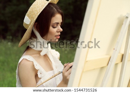 young woman outdoors paints an easel picture