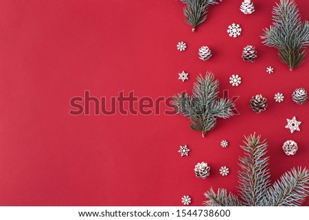 Flat lay christmas border with branches spruce and cones on a red background