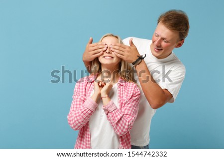 Young couple two friends guy girl in white empty blank design t-shirts posing isolated on pastel blue background studio portrait. People lifestyle concept. Mock up copy space. Looking camera