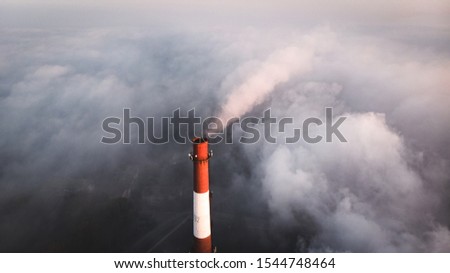 The top of the factory pipe soars and peeps out due to fog, aerial photography.
