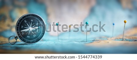 Magnetic compass  and location marking with a pin on routes on world map. Adventure, discovery, navigation, communication, logistics, geography, transport and travel theme concept background. Royalty-Free Stock Photo #1544774339