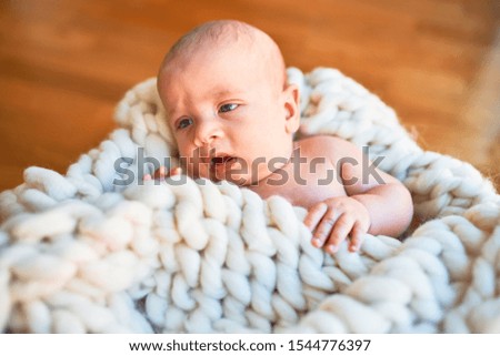 Adorable baby lying down on the floor over blanket at home. Newborn relaxing and resting comfortable