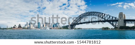 Panorama photo of Sydney Harbour  cityscape and Sydney Harbour Bridge on a blue sky. With white clouds