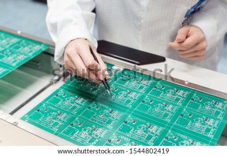 Technician assembling electronic product by inserting components into board on manufacturing line