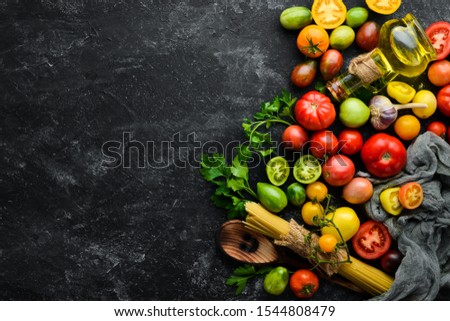 Vegetables. Fresh colored tomatoes On a black stone background. Top view. Free space for your text.