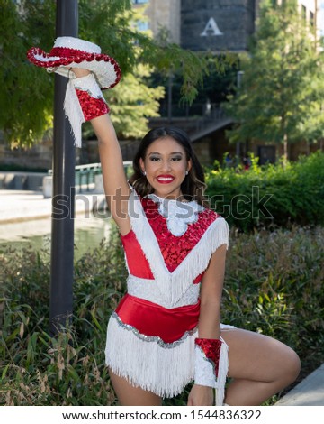 
Young and beautiful Hispanic high school girl in her school dance uniform posing for school pictures