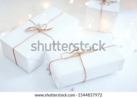 Two white gift boxes tied with a rope on a white background. Christmas and new year concept. bokeh and glare garland