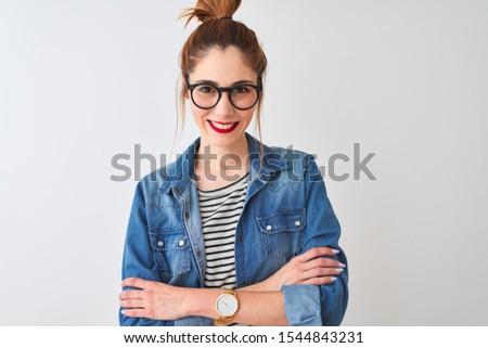 Redhead woman wearing striped t-shirt denim shirt and glasses over isolated white background happy face smiling with crossed arms looking at the camera. Positive person.
