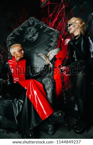 Gothic friends with dark make up in rock outfits on a huge scary throne ready for Halloween party