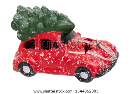 Christmas decorations background. Closeup of a snow-covered red car toy with green fir-tree on the roof isolated on a white background. Saisonal design element for cards or stickers. Macro.