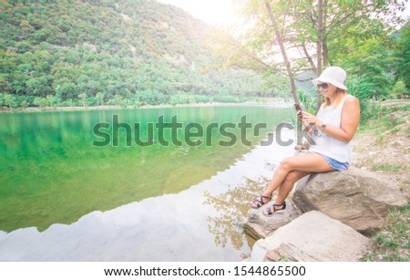 beautriful woman is taking a selfie sit near a lake in a sunny day