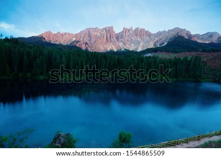 Panoramic view and Dolomites mountains at Carezza lake, Alto Adige or Sudtirol of Italy. Landscape with Karersee and Dolomiti of Alps, Sud Tirol. Alpine scenery of Tyrol. Nature in morning at sunrise