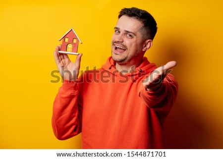 funny man with toy house on yellow background