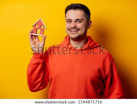 funny man with toy house on yellow background