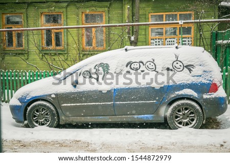 Dirty car in the snow on a village street, funny pictures in the snow by car