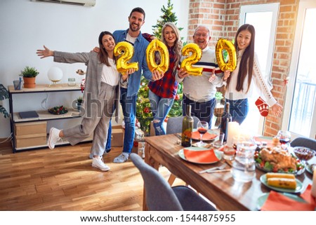 Beautiful family smiling happy and confident. Standing posing with tree holding balloons celebrating New Year at home