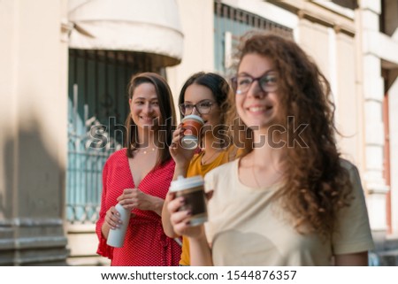 Three young woman shopping together and drinking coffee to go