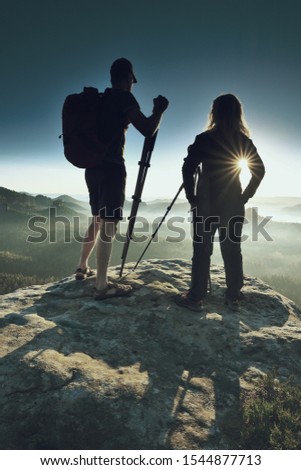 Two photographers meet at sunrise or dawn in the mountains. Blond hair girl with tall slim guy talk about photography.
