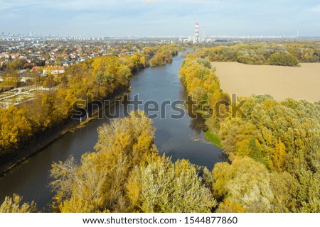 Warsaw. Poland. Epic aerial flight over water. Colorful autumn trees in the daytime. Beautiful river view with autumn trees. Drone flies along a river with yellow trees. Drone Shot 4K.