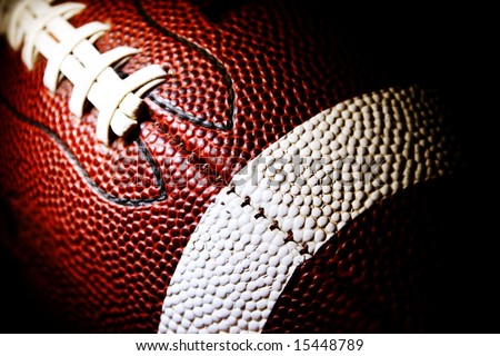 close up of an american football against a black background