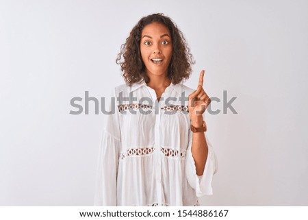 Young brazilian woman wearing shirt standing over isolated white background pointing finger up with successful idea. Exited and happy. Number one.