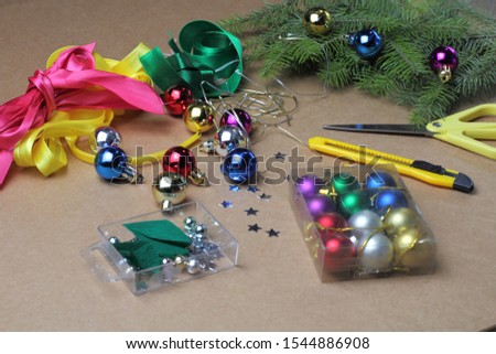 Christmas tree decoration mocap, balls of different colors, scissors, stationery knife, ribbons, spruce branches, craft background.