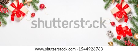Christmas flat lay background with fir tree, present box and decorations on white. Long banner format.