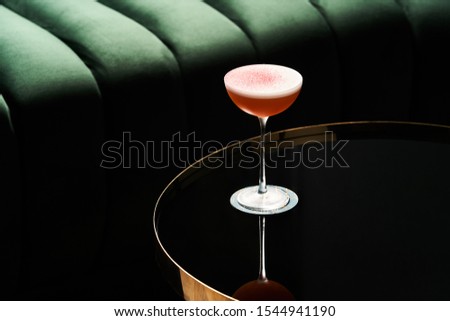 Classic cocktail glass on glass table in night club restaurant. Alcohol cocktail drink, close-up. Modern alcoholic beverage Royalty-Free Stock Photo #1544941190