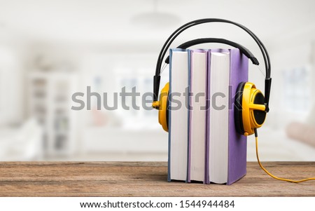 Stack book with headphones on wooden table