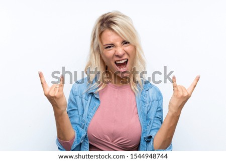 Young blonde woman over isolated white background making rock gesture