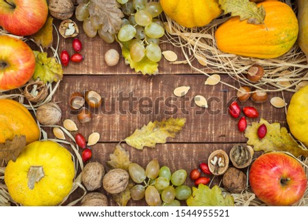 Autumn frame with fruits, pumpkins and nuts on rustic wooden background, top view with copy space. Autumn concept background.