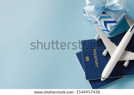 Christmas travel planning. Traveling as gift. White blank model of passenger plane, passports and gift box on blue background. Top view or flat lay. Copy Space. Royalty-Free Stock Photo #1544957438