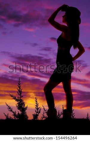 A silhouette of a cowgirl with a hat and boots.