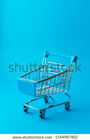 empty metal shopping trolley on blue background. Discount and shopping concept.