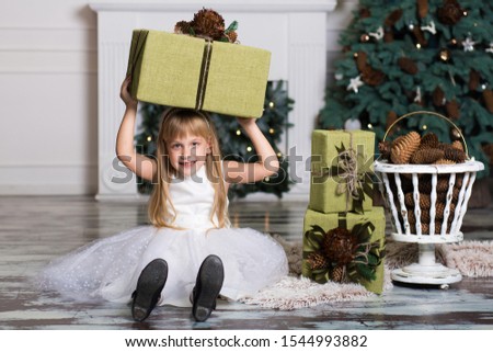 Happy girl holding a big box with a gift over her head. winter holidays, christmas and people concept.