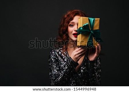 Gorgeous european girl expressing positive emotions at birthday party. Graceful ginger model posing with christmas present