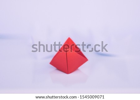 Leadership concept with red paper ship leading among group of white ships on white background.