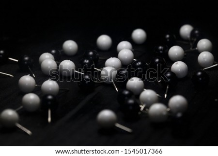 Black and white pins scattered on a black surface 