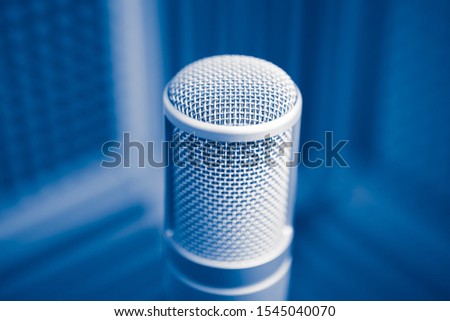 professional microphone in sound recording studio, blue acoustic foam background