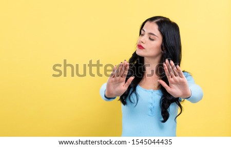 Young woman making a rejection pose on a yellow background