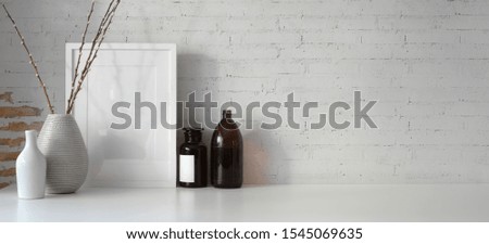 Minimal workspace with mock up frame and copy space, white desk and vintage brick wall background 