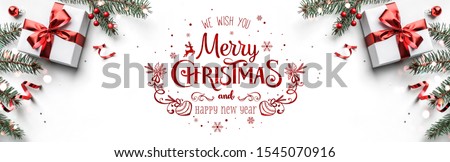Merry Christmas text on white background with gift boxes, ribbons, red decoration, fir branches, bokeh, sparkles and confetti. Xmas and New Year greeting card, bokeh, light. Flat lay, top view