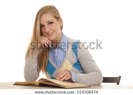 A school girl has a book open looking up and smiling.