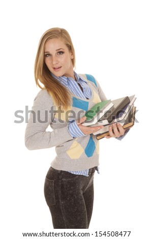 A school girl is holding a stack of books looking and smiling.