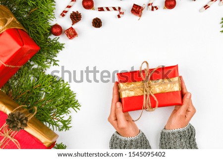 Female hands give a gift top view. Female hands holding a gift with a red bow on a white background with a New Year's decorator. Festive background for the holidays: birthday, Valentine's Day